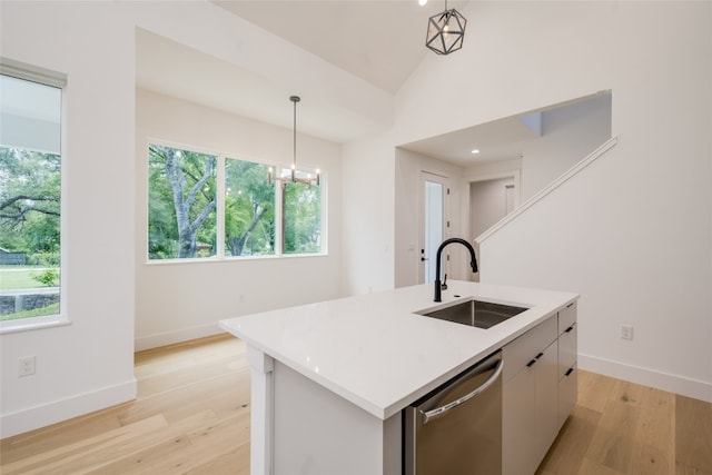 kitchen with stainless steel dishwasher, sink, a center island with sink, a healthy amount of sunlight, and light wood-type flooring