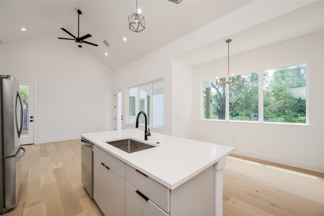 kitchen with a kitchen island with sink, vaulted ceiling, light hardwood / wood-style floors, sink, and stainless steel appliances