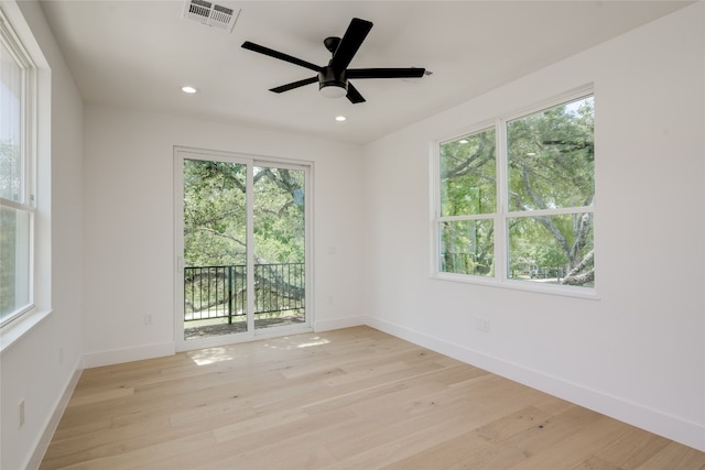 empty room featuring plenty of natural light, ceiling fan, and light hardwood / wood-style flooring