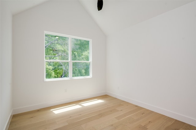 spare room featuring light hardwood / wood-style flooring, lofted ceiling, and plenty of natural light