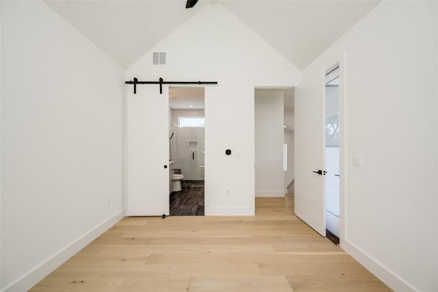 1928 Miles Ave Unit 2, Austin, TX 78745 - unfurnished bedroom featuring a barn door, light wood-style flooring, baseboards, ensuite bath, and high vaulted ceiling