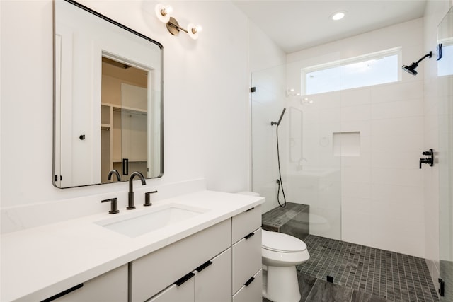 bathroom with tile patterned floors, toilet, a tile shower, and vanity