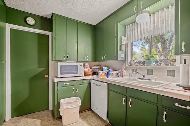 kitchen with green cabinets, light countertops, white appliances, and a sink