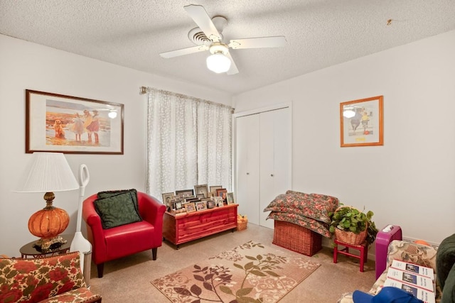 living area with light colored carpet, ceiling fan, and a textured ceiling