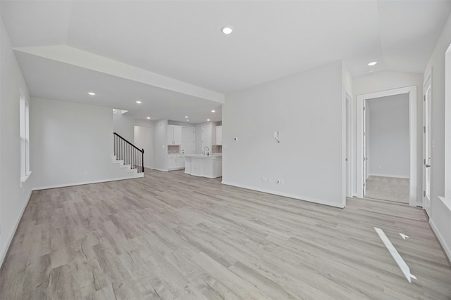 unfurnished living room featuring lofted ceiling and light wood-type flooring