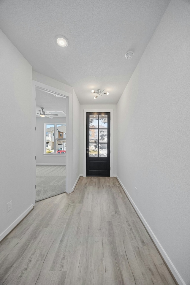 doorway to outside with a textured ceiling and light hardwood / wood-style flooring