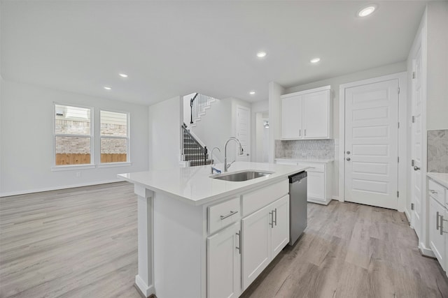 kitchen featuring white cabinetry, stainless steel dishwasher, sink, and a center island with sink