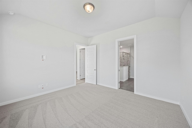 unfurnished bedroom featuring lofted ceiling, light carpet, and ensuite bathroom