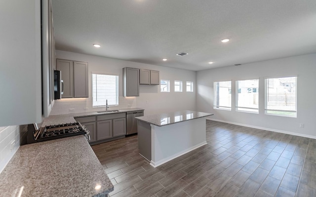 kitchen featuring appliances with stainless steel finishes, a kitchen island, dark hardwood / wood-style flooring, and a healthy amount of sunlight