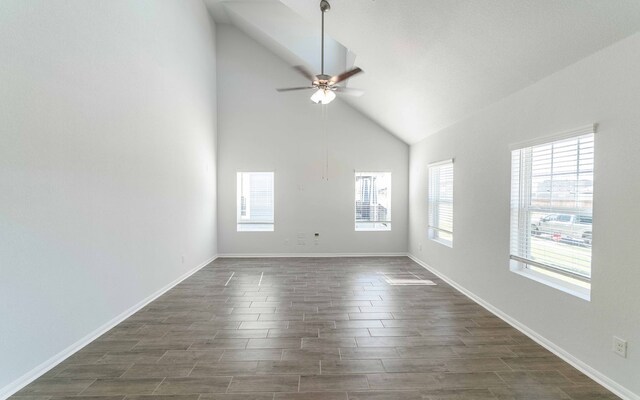 empty room featuring ceiling fan, dark hardwood / wood-style floors, high vaulted ceiling, and a wealth of natural light