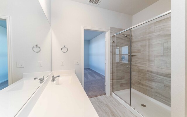 bathroom with hardwood / wood-style floors, a shower with shower door, and vanity