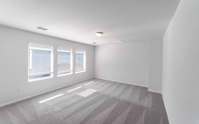 carpeted empty room featuring a textured ceiling