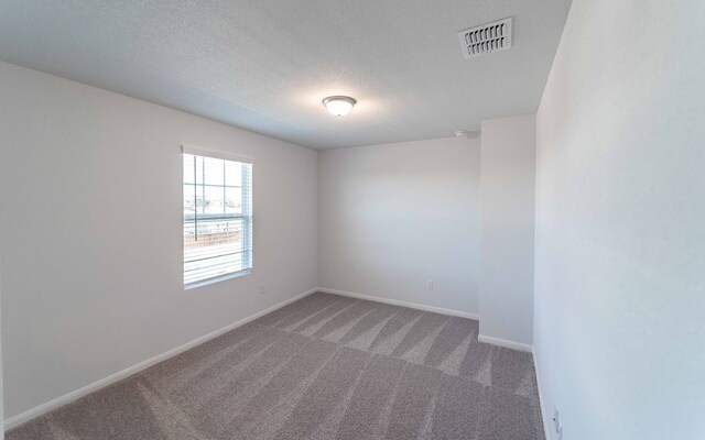 carpeted empty room featuring a textured ceiling