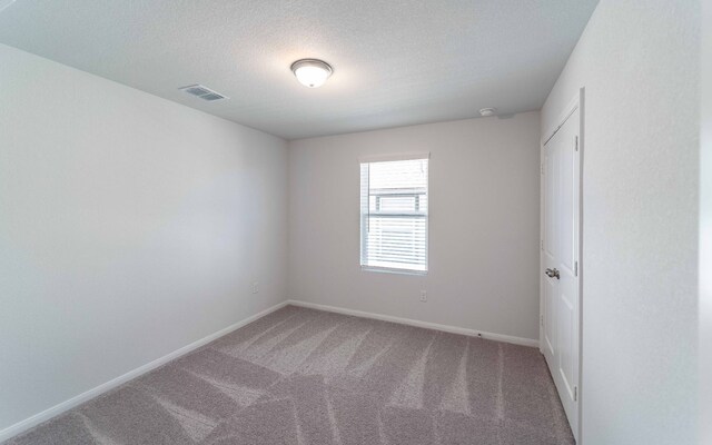 carpeted empty room with a textured ceiling