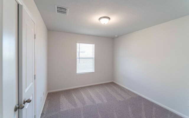 carpeted empty room with a textured ceiling