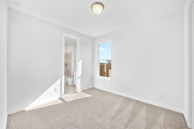 unfurnished bedroom featuring light carpet and connected bathroom