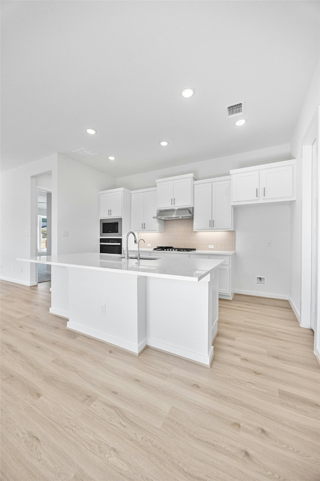 kitchen featuring appliances with stainless steel finishes, a large island, light hardwood / wood-style flooring, and white cabinets