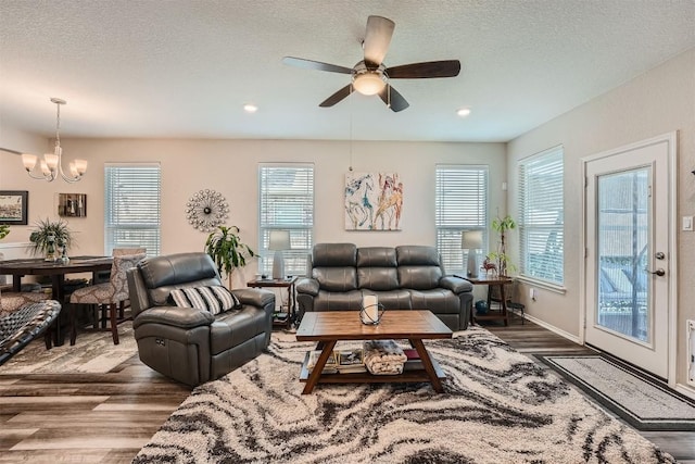 living room with hardwood / wood-style floors, ceiling fan with notable chandelier, a textured ceiling, and a wealth of natural light