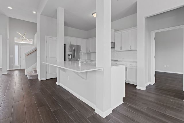 kitchen with white cabinetry, sink, a kitchen breakfast bar, stainless steel fridge with ice dispenser, and a kitchen island with sink