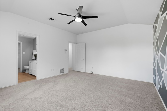 unfurnished bedroom with vaulted ceiling, light carpet, ceiling fan, and ensuite bath