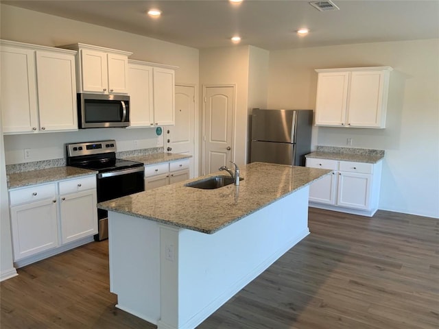 kitchen with stainless steel appliances, a kitchen island with sink, sink, and white cabinets