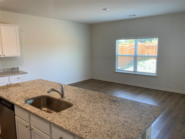 kitchen featuring stainless steel dishwasher, wood-type flooring, white cabinets, light stone countertops, and sink