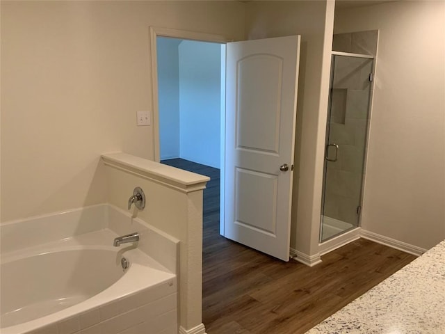 bathroom featuring wood-type flooring and shower with separate bathtub