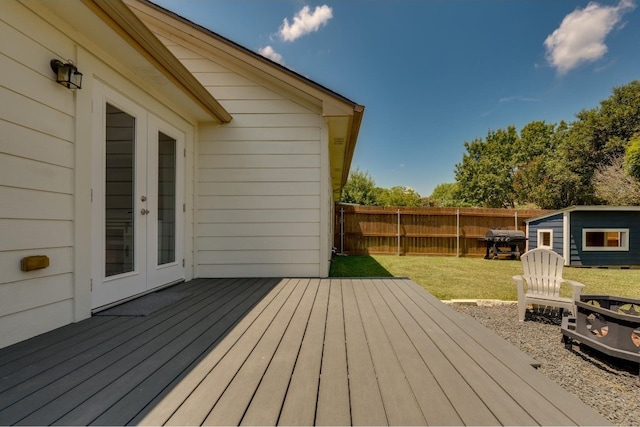 deck with an outdoor structure, french doors, and a lawn