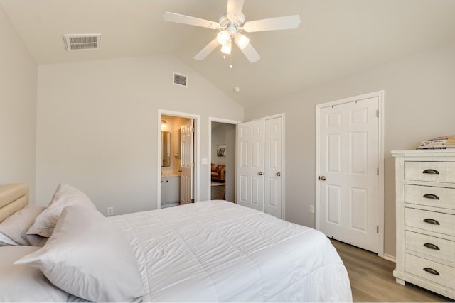 bedroom with ceiling fan, vaulted ceiling, connected bathroom, and light hardwood / wood-style floors