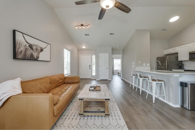 living room with light wood-type flooring, high vaulted ceiling, and ceiling fan