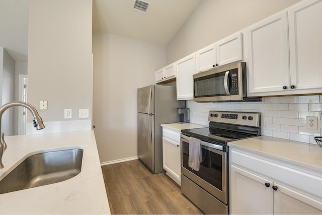 kitchen with tasteful backsplash, white cabinetry, light hardwood / wood-style floors, sink, and stainless steel appliances