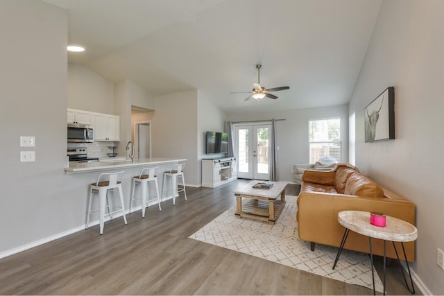 living room featuring ceiling fan, french doors, hardwood / wood-style flooring, sink, and lofted ceiling