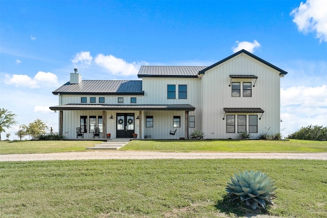 modern farmhouse featuring french doors, covered porch, board and batten siding, and a chimney