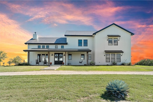 modern farmhouse style home featuring french doors, covered porch, board and batten siding, and metal roof