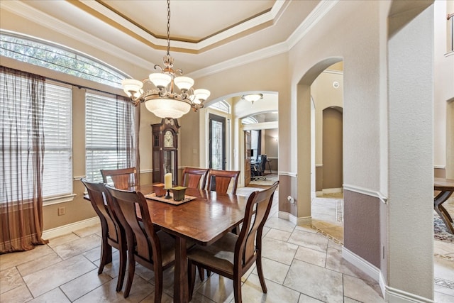 tiled dining space with a tray ceiling, crown molding, and an inviting chandelier