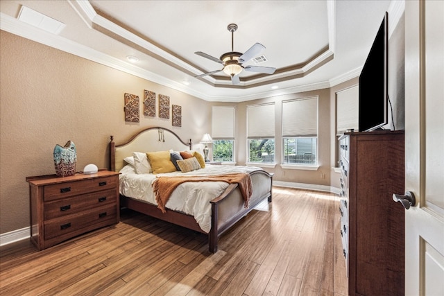 bedroom featuring ceiling fan, a tray ceiling, light hardwood / wood-style floors, and ornamental molding