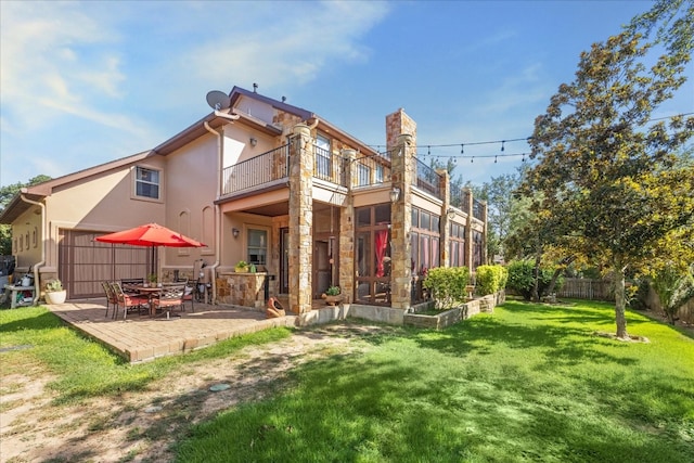 rear view of house with a balcony, a patio area, and a lawn