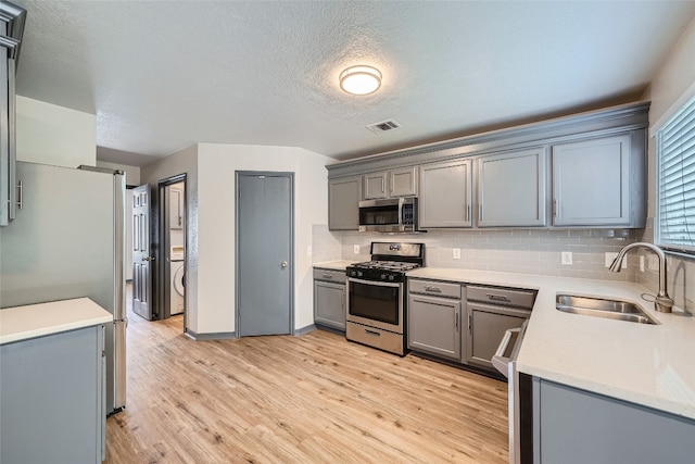 kitchen featuring sink, light hardwood / wood-style floors, gray cabinets, and stainless steel appliances