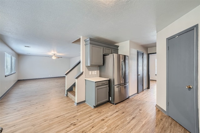 kitchen with light hardwood / wood-style flooring, backsplash, gray cabinetry, stainless steel refrigerator, and a textured ceiling