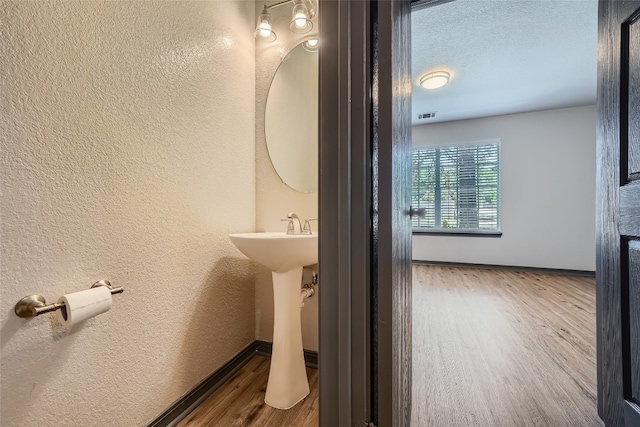 bathroom with a textured ceiling and wood-type flooring