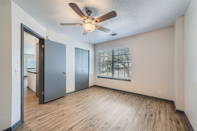 unfurnished bedroom featuring ceiling fan, light hardwood / wood-style floors, and a textured ceiling