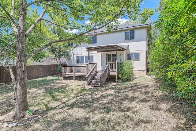 back of property with a wooden deck and a lawn