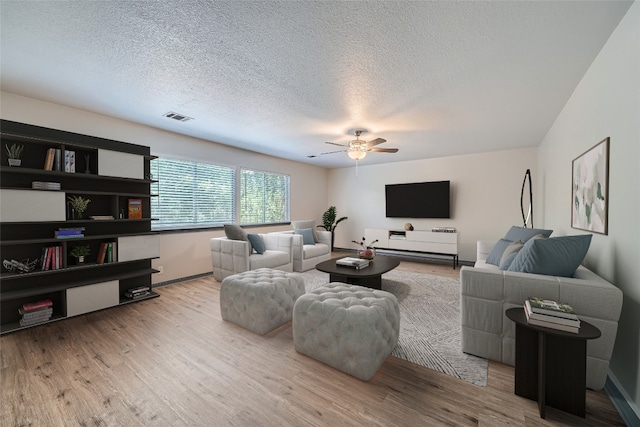 living room featuring a textured ceiling, light hardwood / wood-style flooring, and ceiling fan