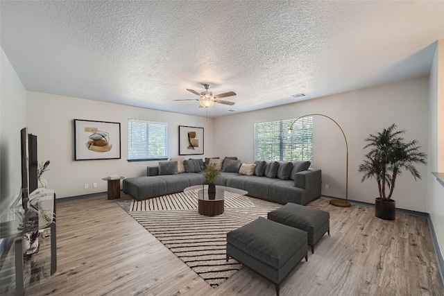 living room with ceiling fan, light hardwood / wood-style flooring, and a textured ceiling