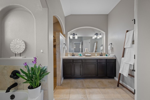 bathroom with tile patterned flooring, lofted ceiling, and dual vanity