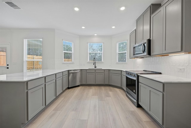 7005 Taruca Ln, Austin, TX 78736 - kitchen featuring appliances with stainless steel finishes, gray cabinets, a peninsula, ornamental molding, and recessed lighting