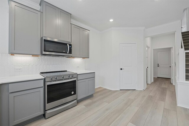 7005 Taruca Ln, Austin, TX 78736 - kitchen with gray cabinets, stainless steel appliances, light wood-style floors, light countertops, and ornamental molding