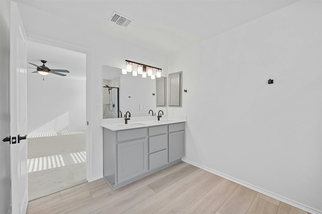7005 Taruca Ln, Austin, TX 78736 - full bathroom featuring wood finished floors, an enclosed shower, ceiling fan, double vanity, and baseboards