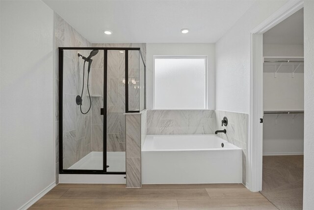 7005 Taruca Ln, Austin, TX 78736 - bathroom featuring a bath, a stall shower, a spacious closet, and wood finished floors