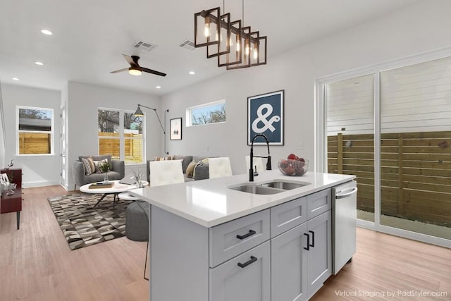 kitchen featuring visible vents, dishwasher, open floor plan, light countertops, and a sink